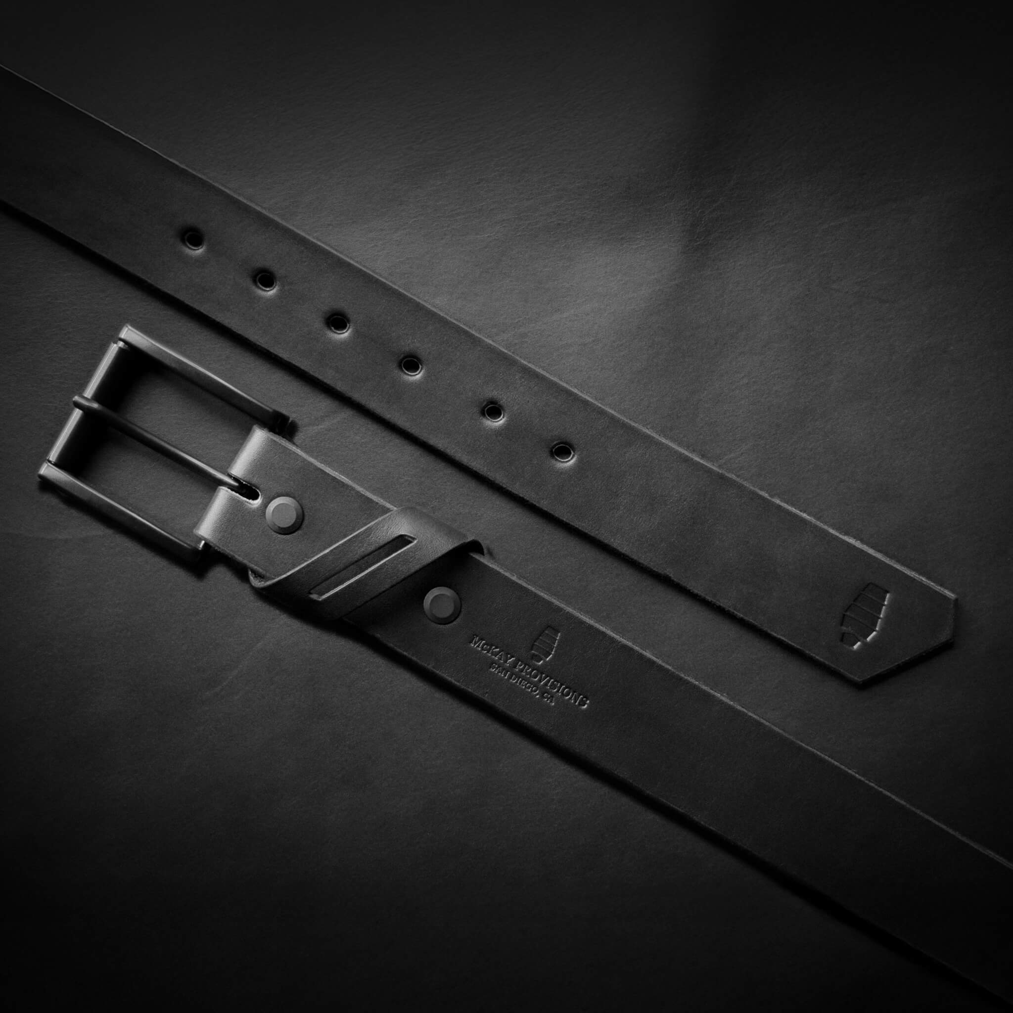 Black leather belt with a black buckle on a black leather background