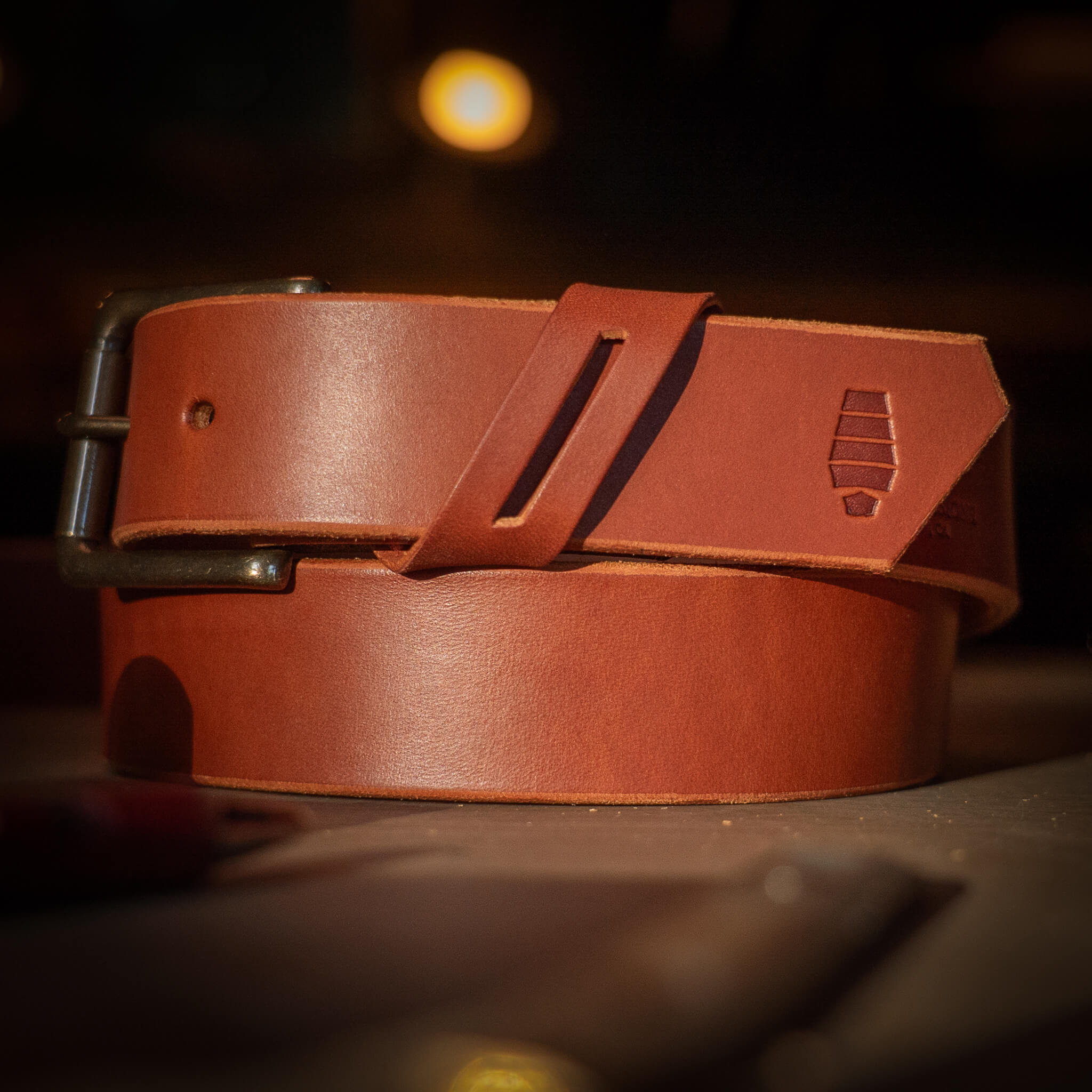 Brown leather belt with a buckle on a dark background