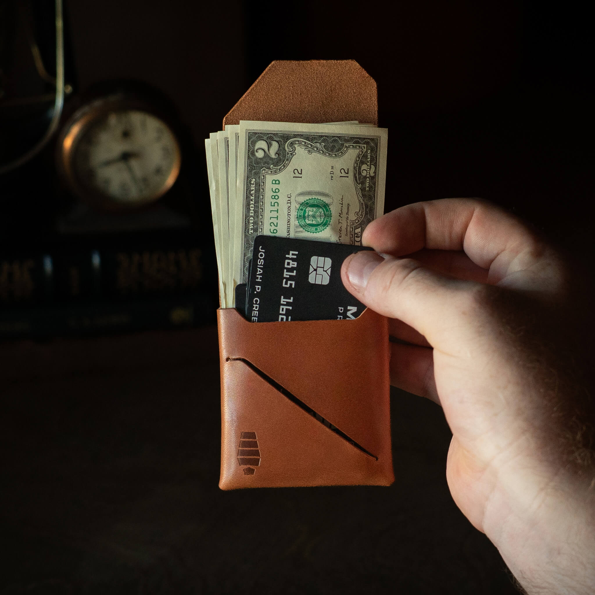 Hand pulling credit card from Voyager wallet Tuck & Go billfold pocket demonstrating unfolded cash access feature.