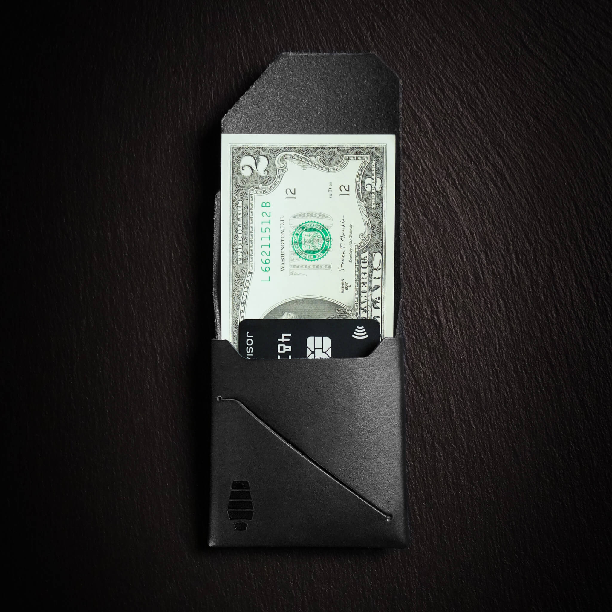 Voyager minimalist wallet in Midnight Black unfolded and open showing cash visible in Tuck & Go billfold pocket and its slim profile with stitchless leather construction