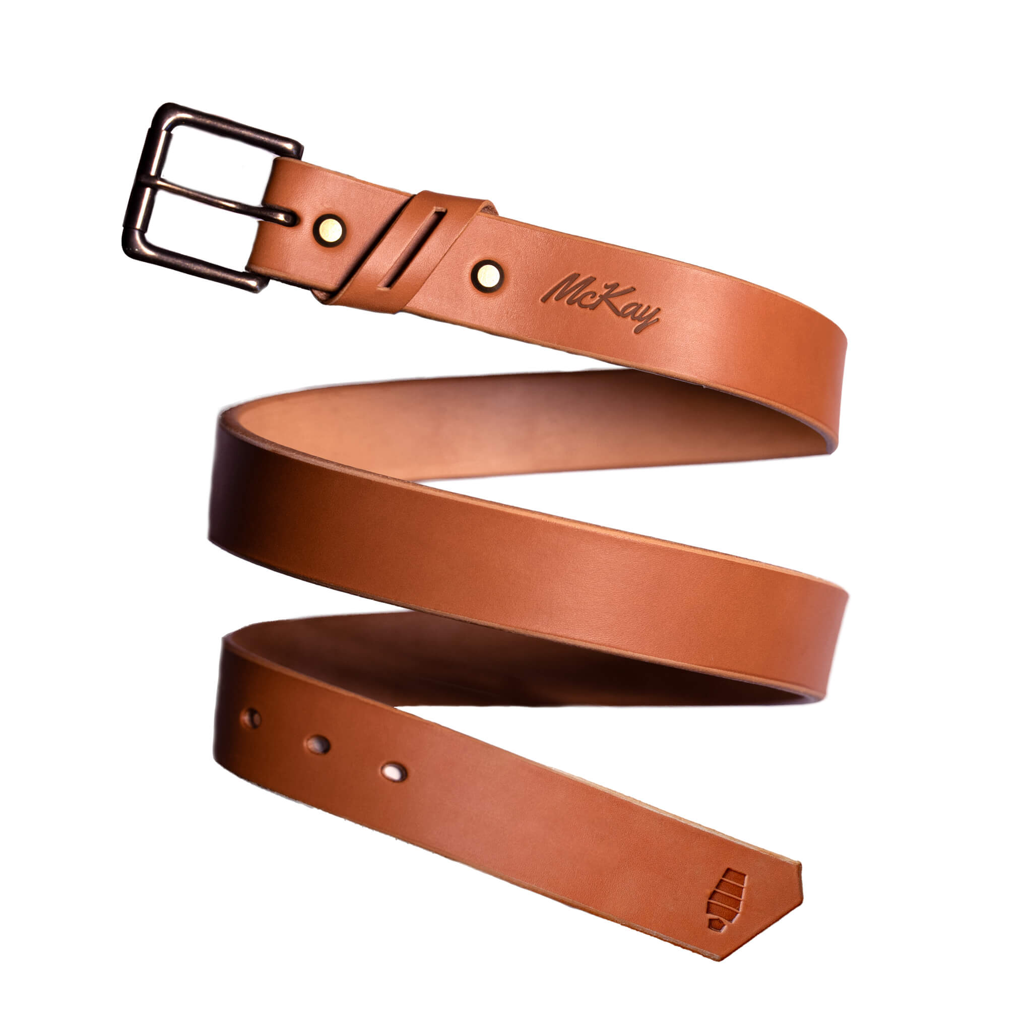 A handcrafted full-grain leather belt in rich chestnut brown, coiled in a dynamic spiral against a white background. The belt features a solid antique brass buckle, double keeper loops, and the embossed McKay logo near the buckle, with a signature angled tip and stamped emblem at the end — representing McKay Provisions’ Mainstay Belt.