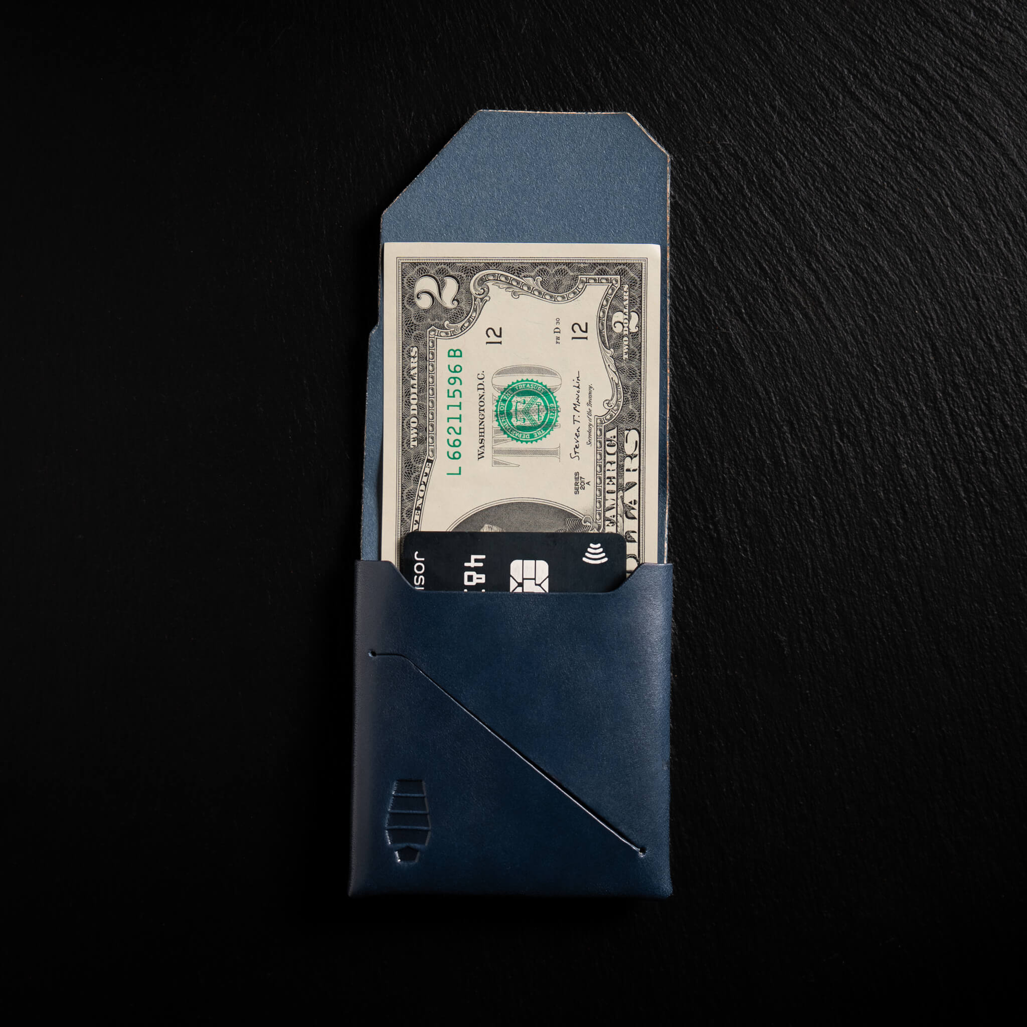 Voyager minimalist wallet in Abyss Navy unfolded and open showing cash visible in Tuck & Go billfold pocket and its slim profile with stitchless leather construction