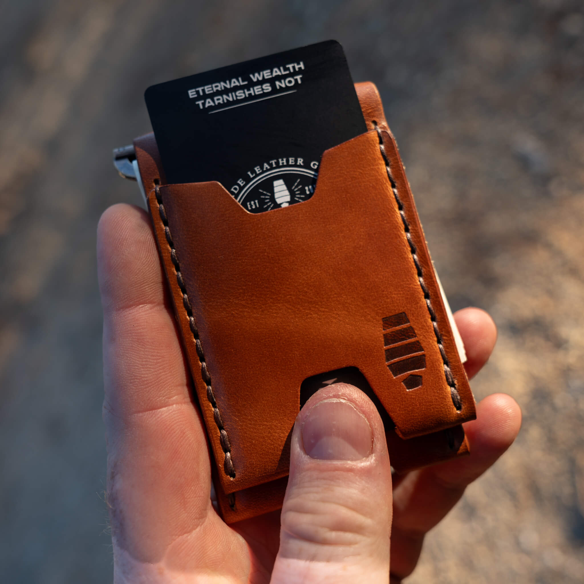 Hand pushing card out of Windward wallet using front quick-access slot